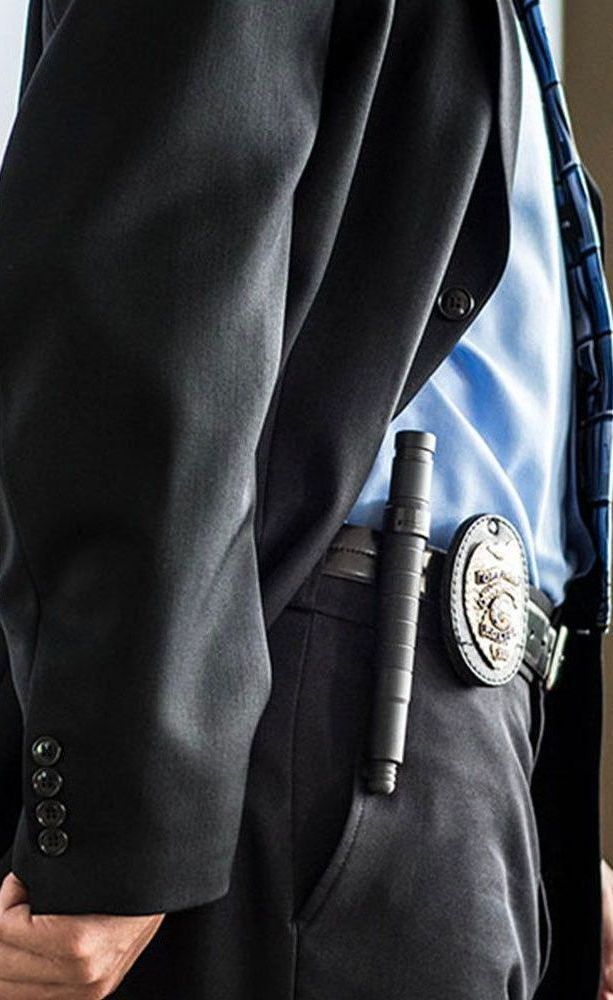 A man in a suit and tie has a badge on his belt.