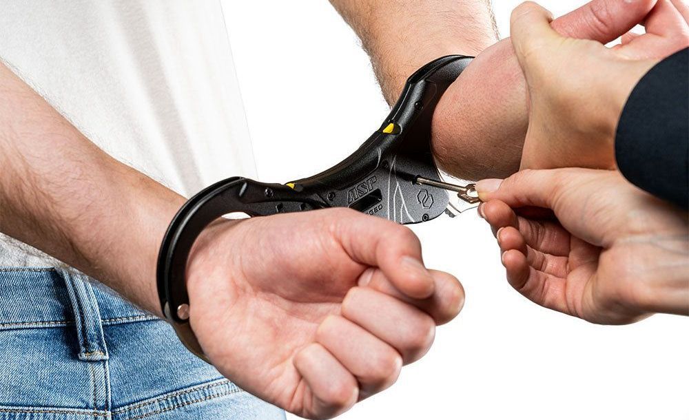 A man in handcuffs is being handcuffed by another person.