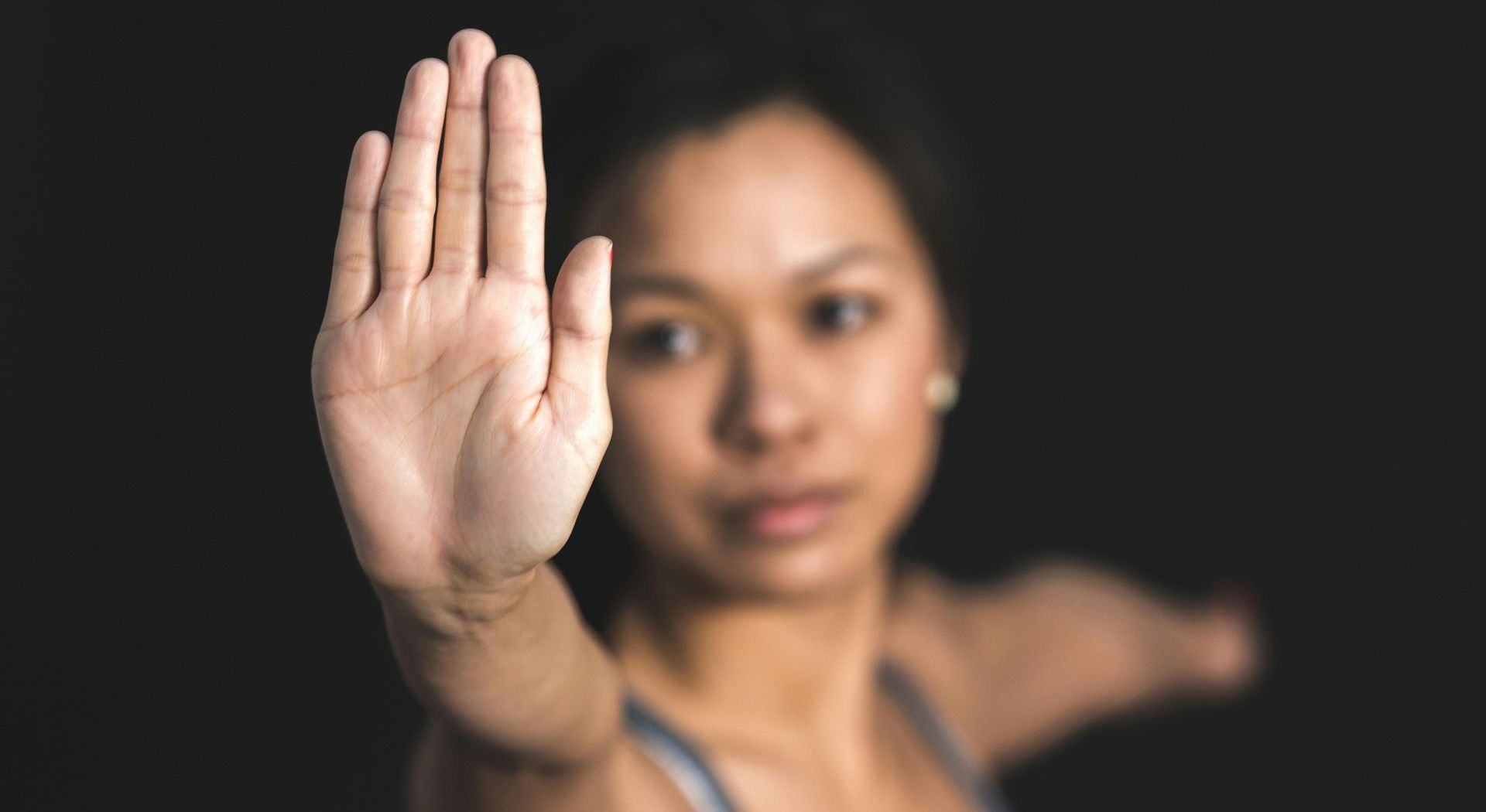 A woman is making a stop sign with her hand.