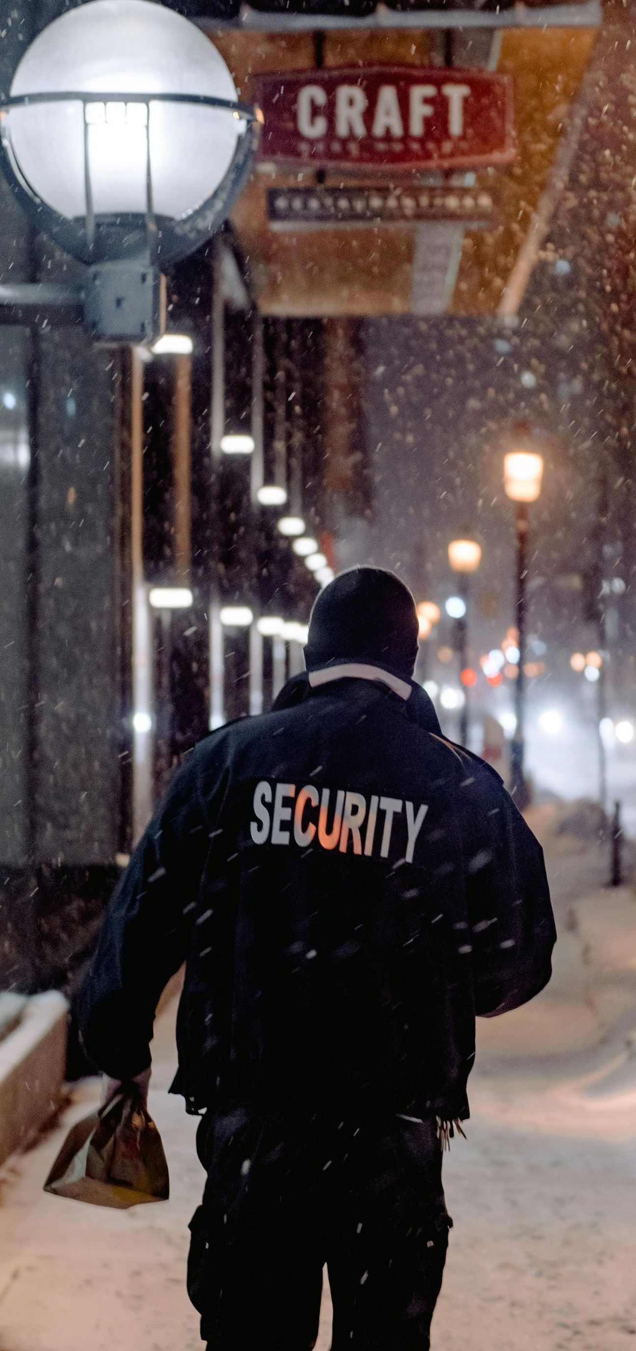 A security guard is walking down a snowy street.