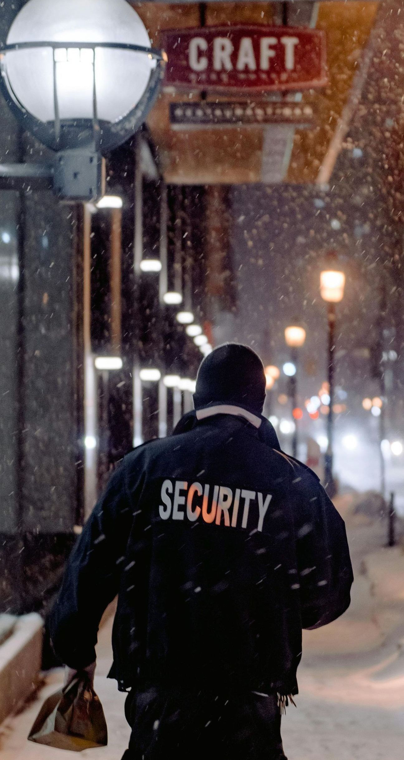 A security guard is walking down a snowy street.