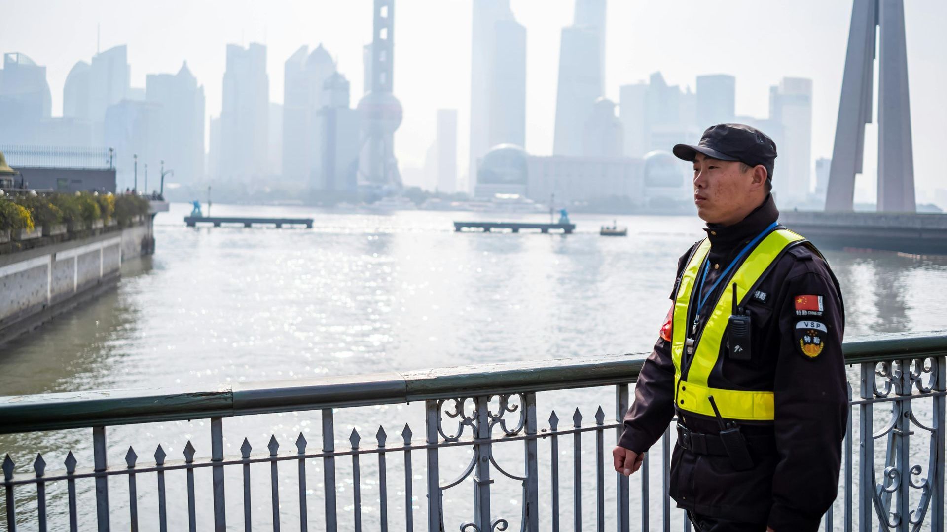 A security guard is standing on a bridge overlooking a river.