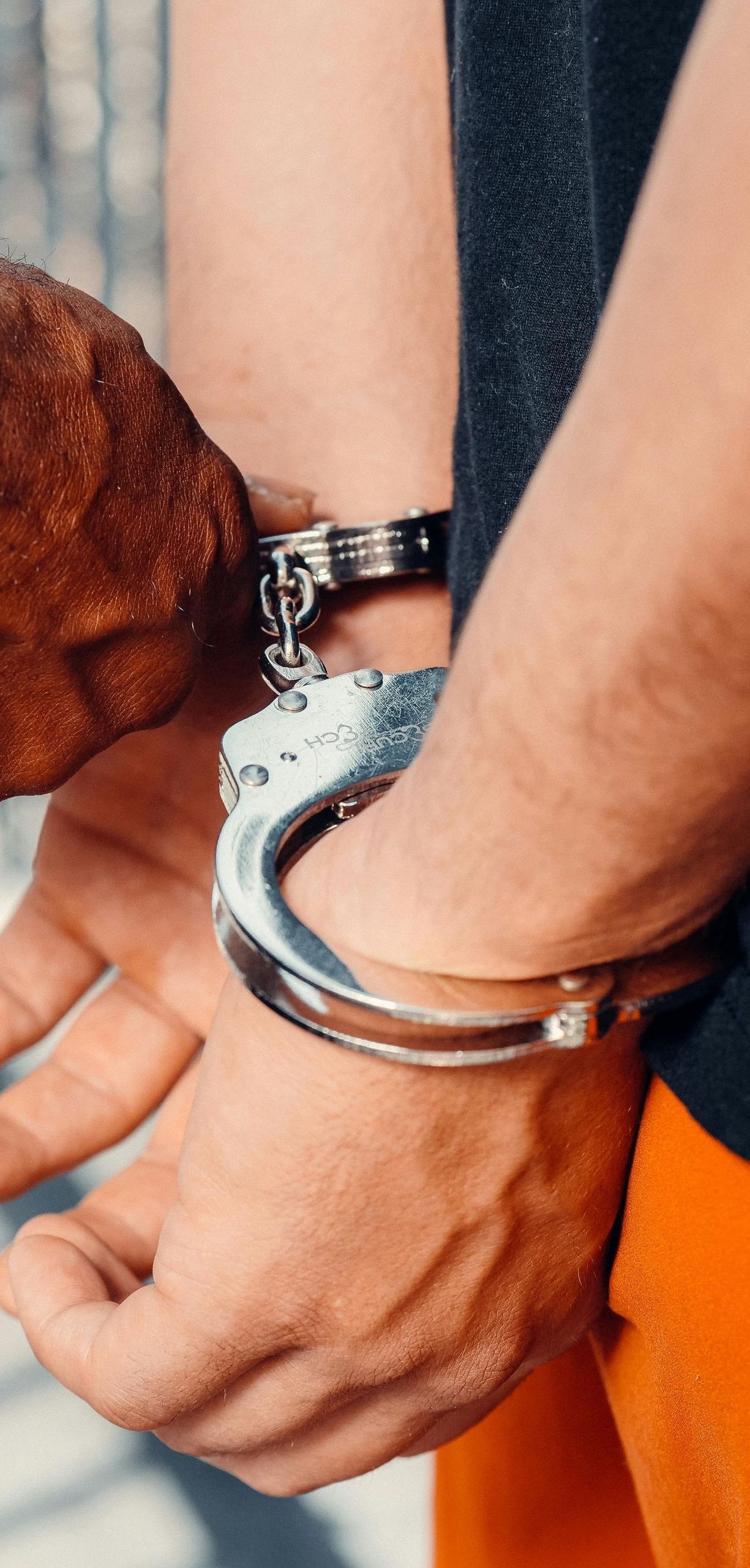 A man in handcuffs is holding a piece of wood.