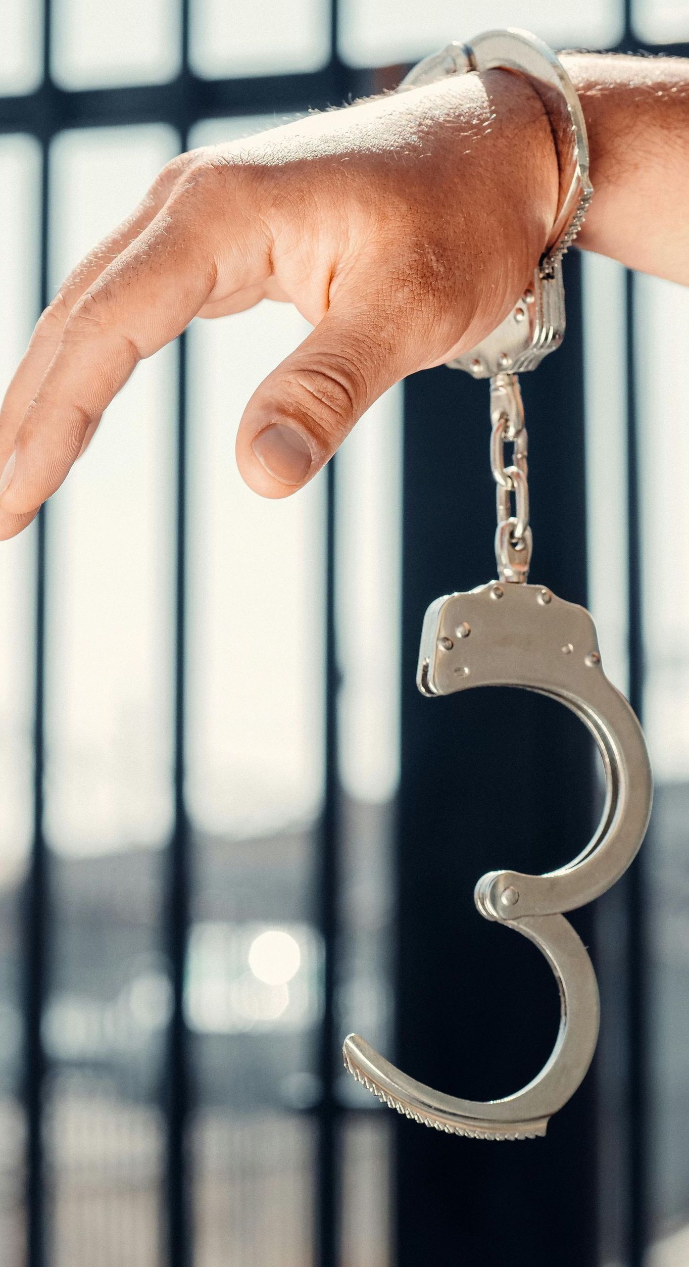 A person is holding a pair of handcuffs on their wrist.