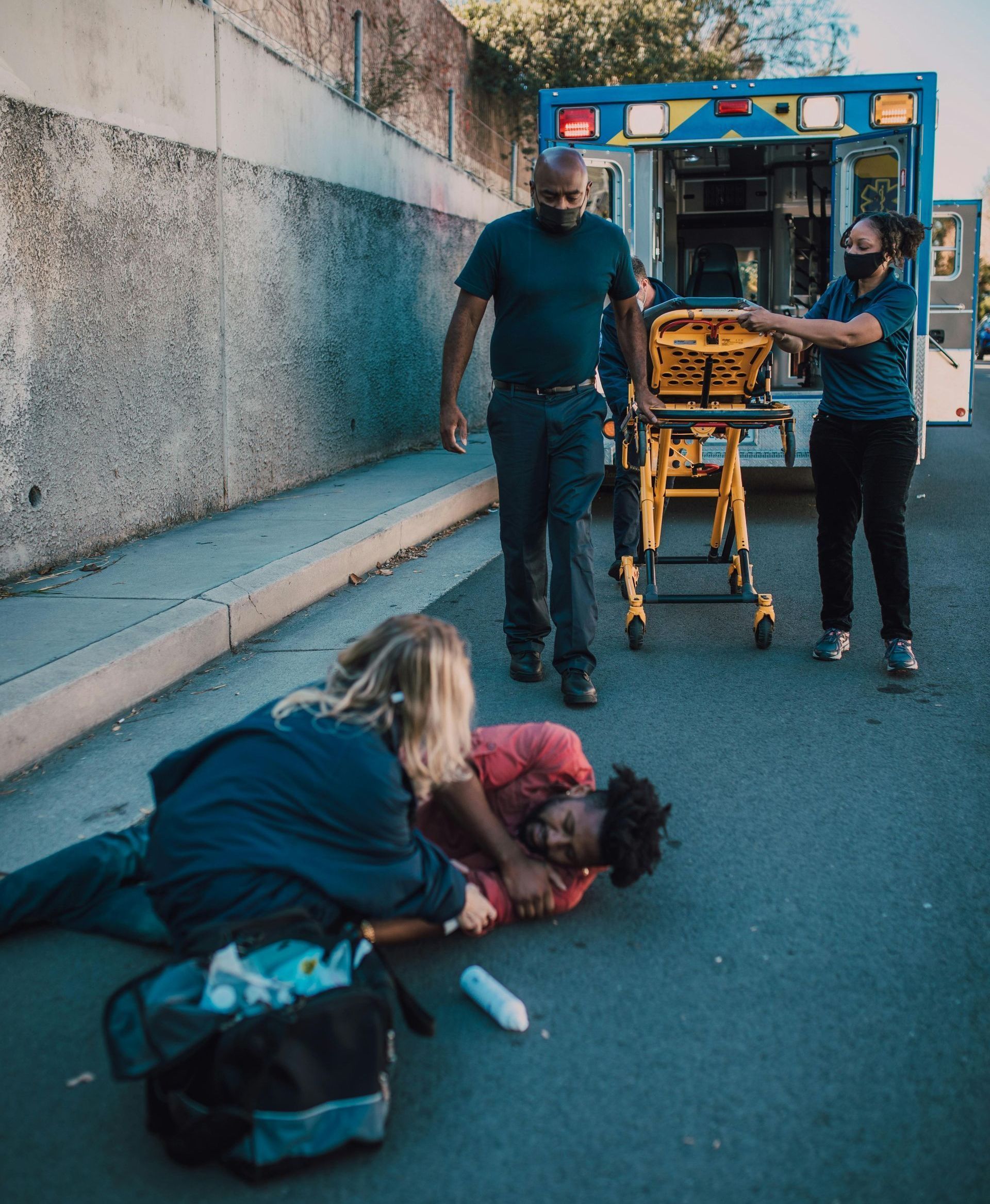 A man is laying on the ground with an ambulance in the background.