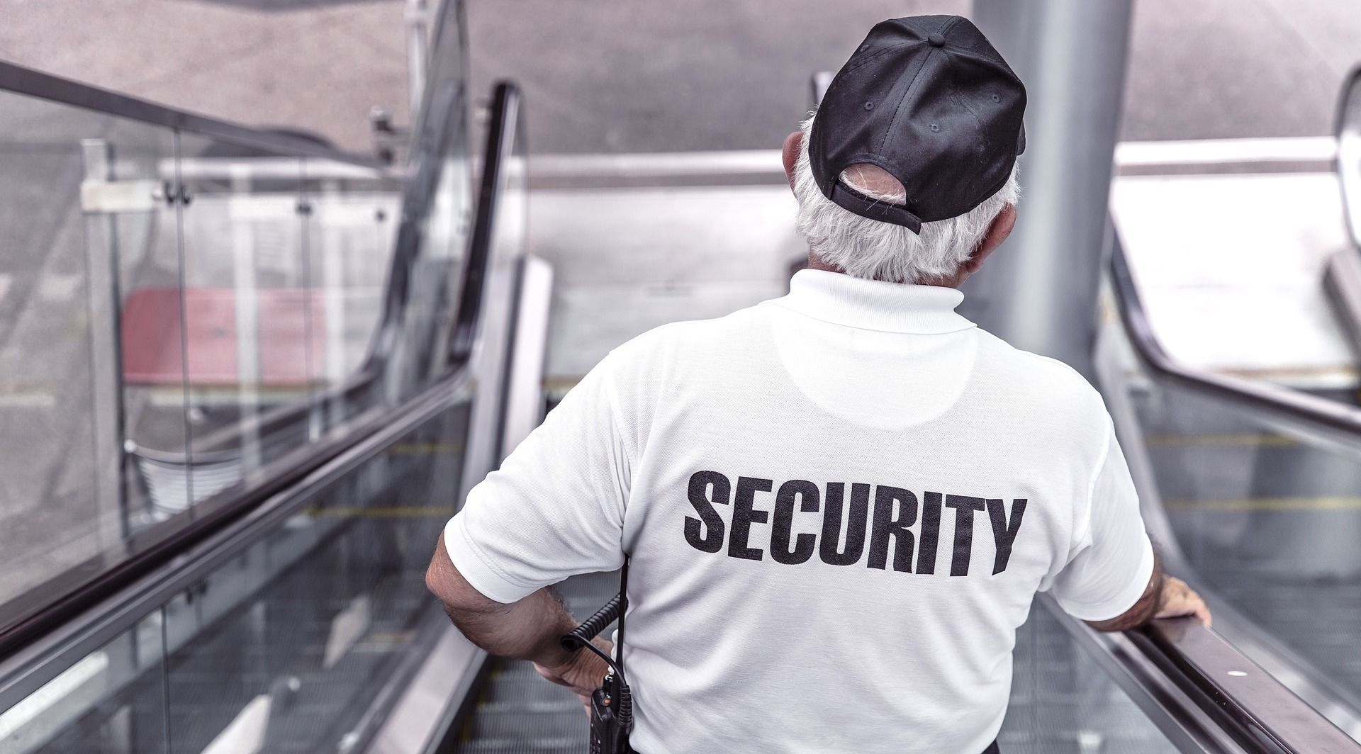 A security guard is walking down an escalator.