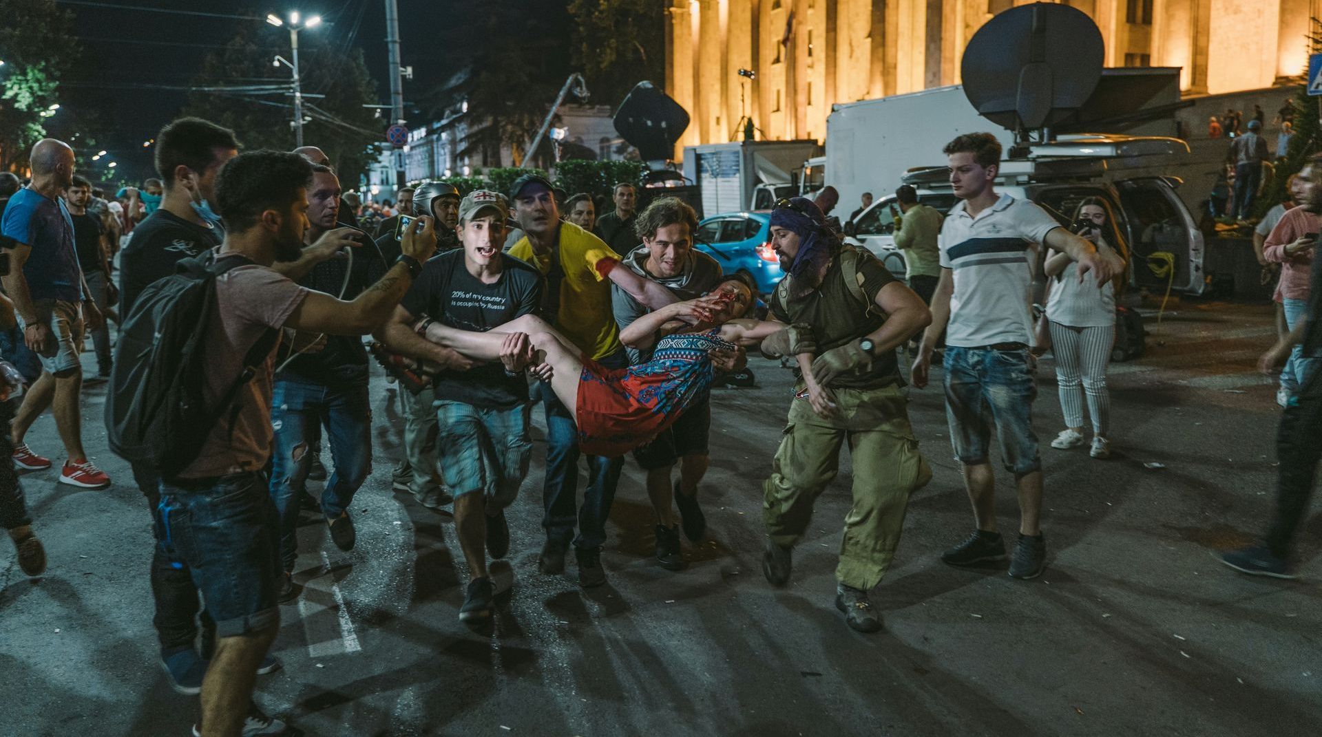 A group of people are walking down a street at night.