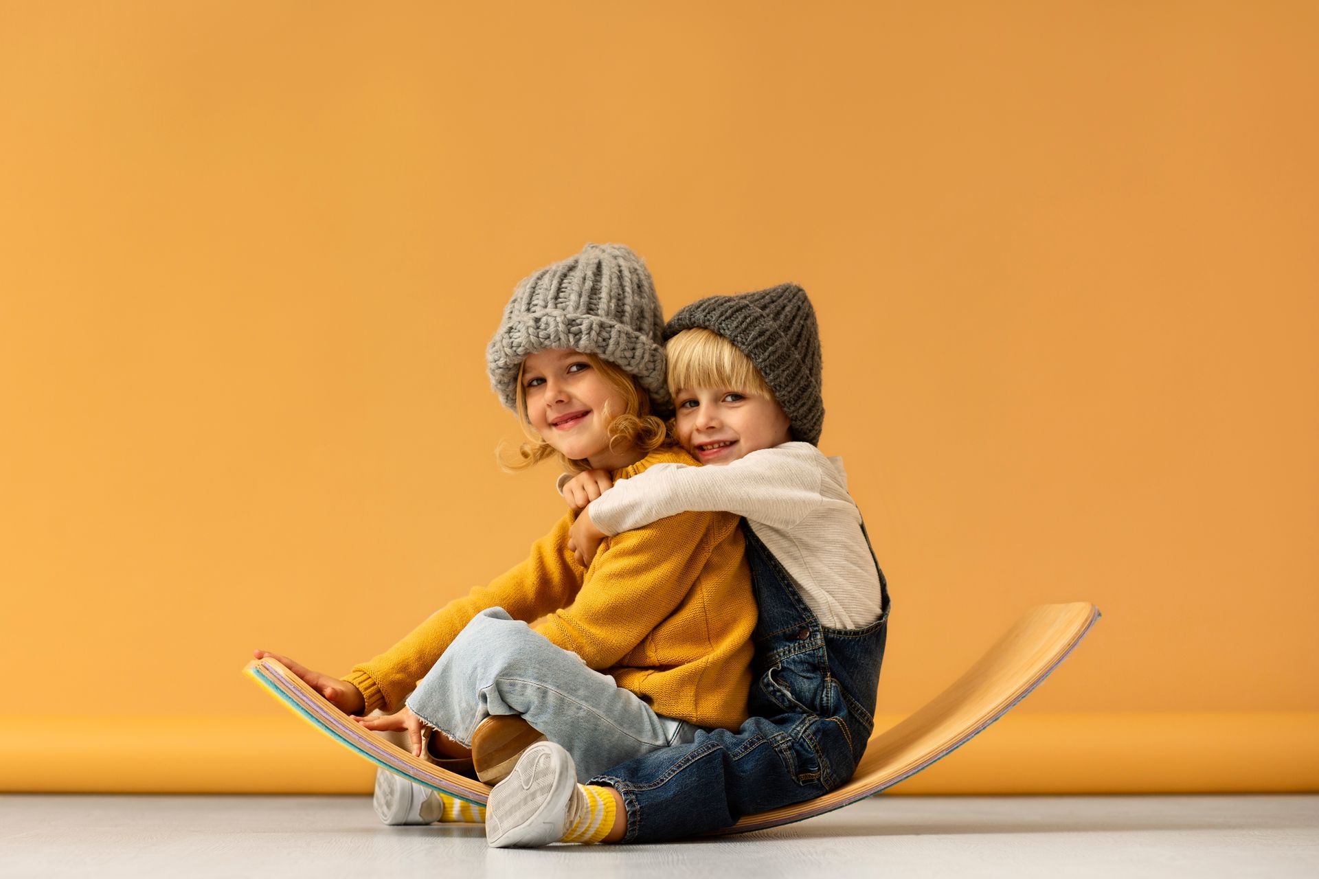 Un niño y una niña están sentados en una patineta.