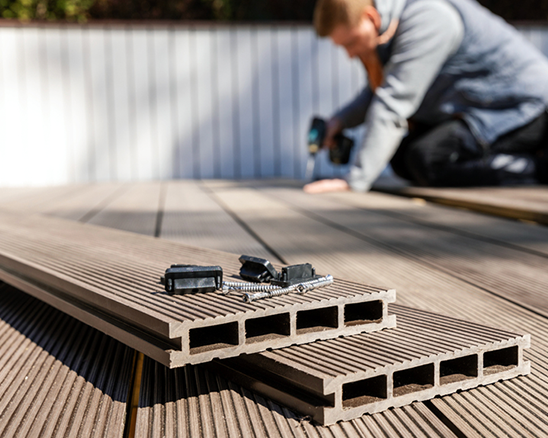 A man is installing a wooden deck with a drill.