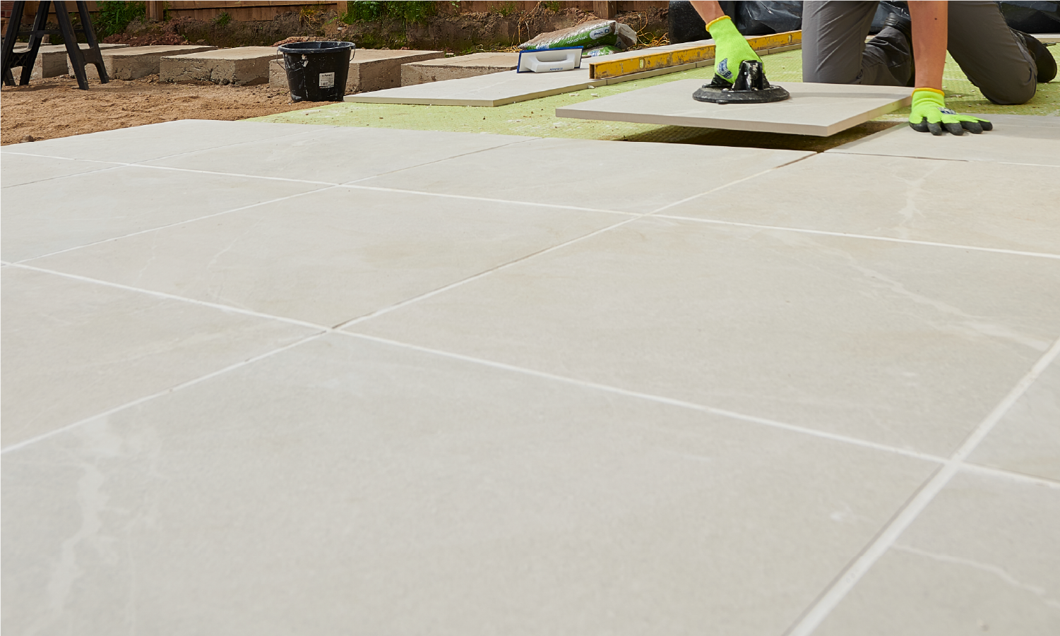 A man is laying tiles on a patio.