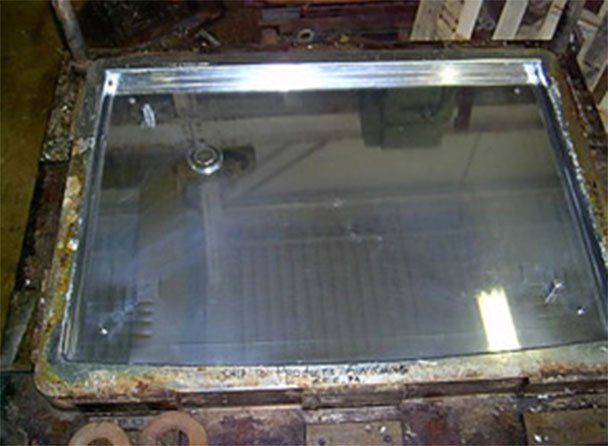 a large piece of glass is sitting on top of a metal tray .