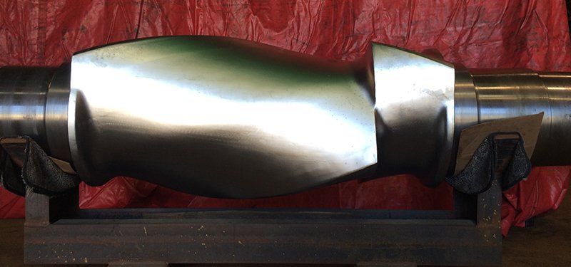 a large metal object is sitting on a wooden block in front of a red tarp