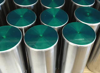 a close up of a bunch of metal cylinders with green lids .