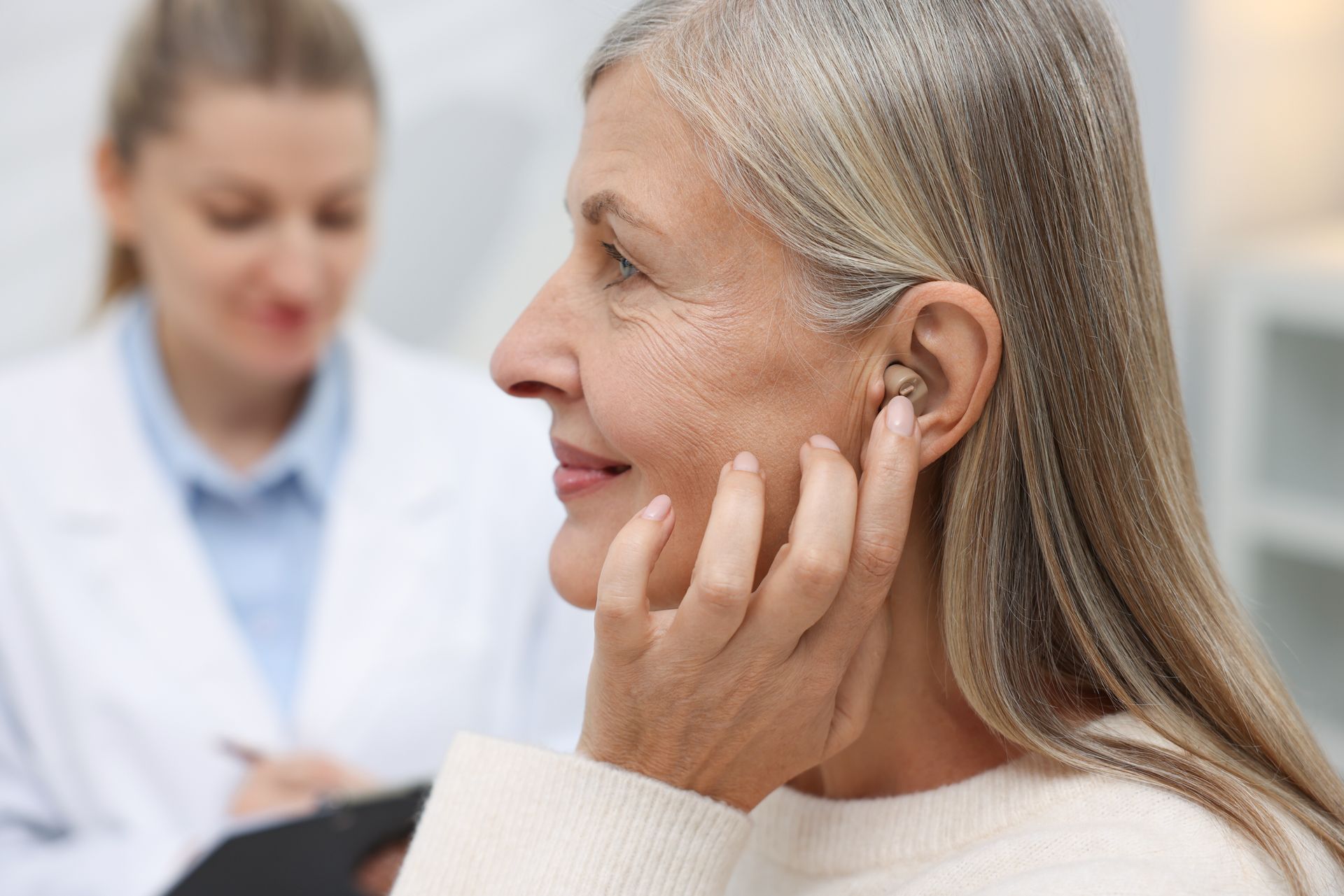 Senior woman wearing a hearing aid at a doctor's appointment in a clinic.