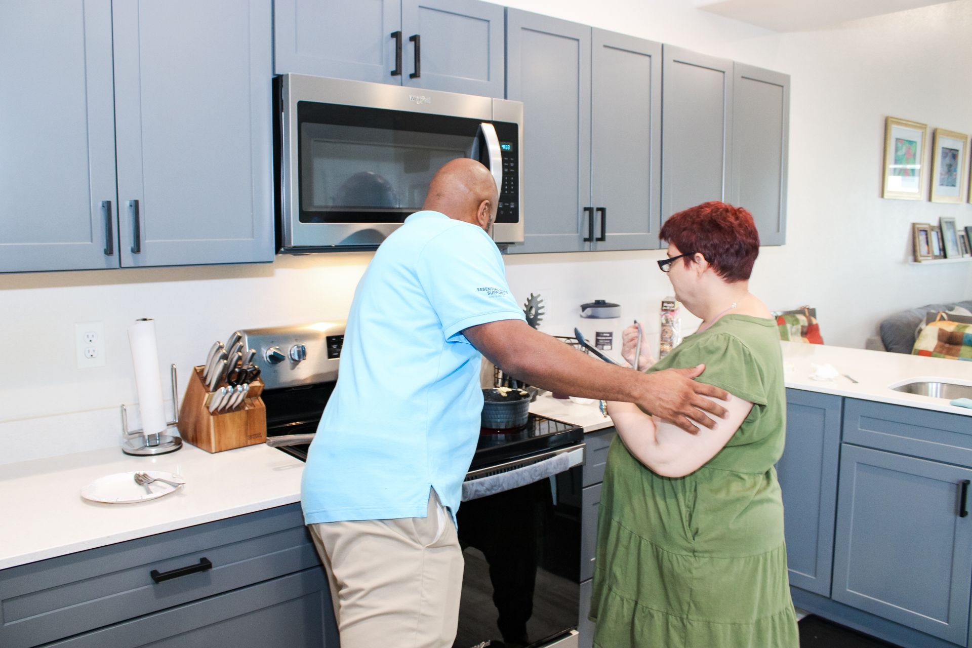 Caregiver supporting daily living activities for an adult in a home-based care kitchen