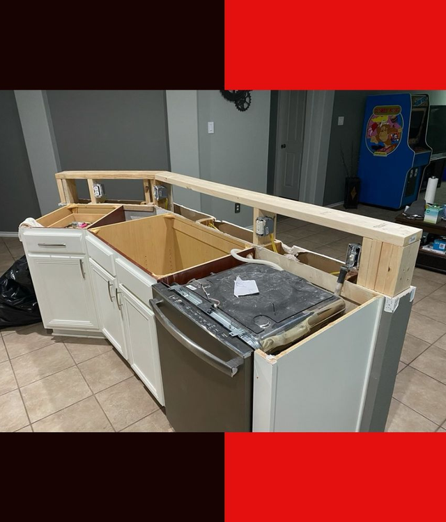 Kitchen cabinets removed, exposing countertops, sink, and plywood framing during renovation.