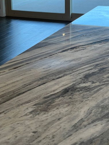 Marble tabletop with gray veining near a window on a dark wood floor