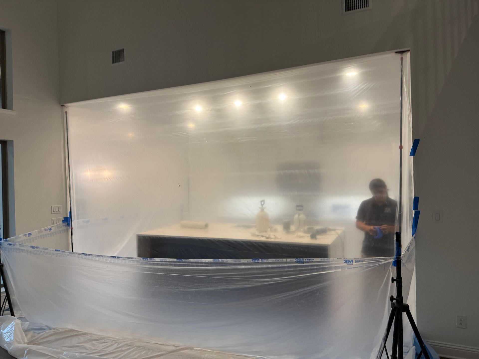 Large clear display panel in a hall, lit by overhead lights, with a person standing beside it and a barrier in front.