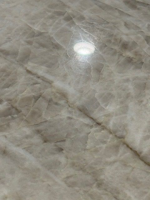 Close-up of a beige marble or stone surface with a bright light reflection.