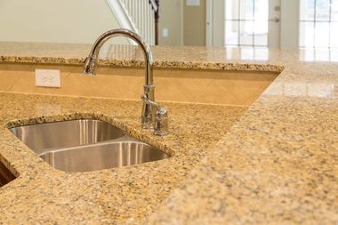 Granite kitchen countertop with stainless steel sink and curved faucet