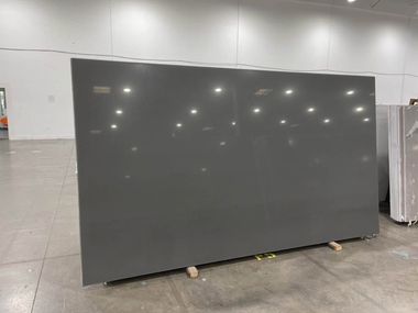 Large dark gray panel leaning on blocks in a warehouse or showroom floor