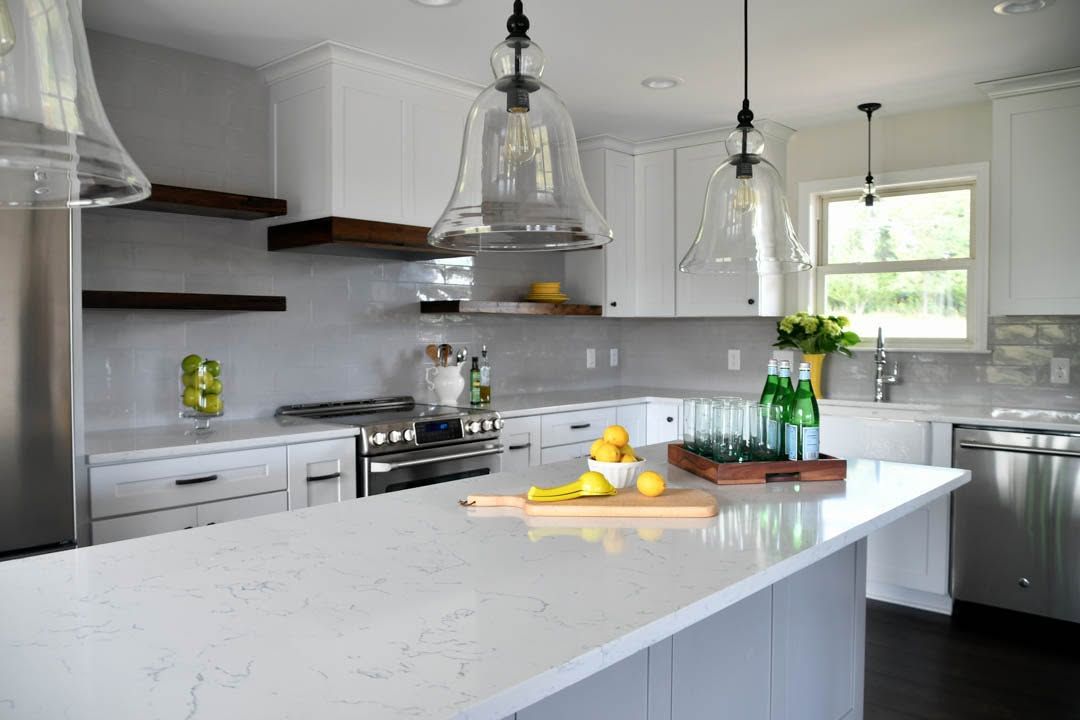 Bright modern kitchen with white island, hanging lights, and fruit on the counter
