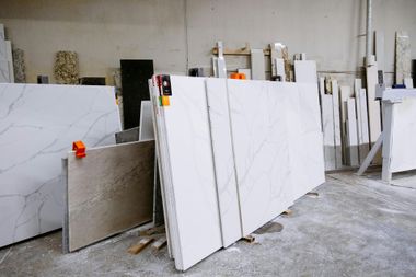 Large white marble slabs stored upright in a warehouse, with smaller stone samples nearby.