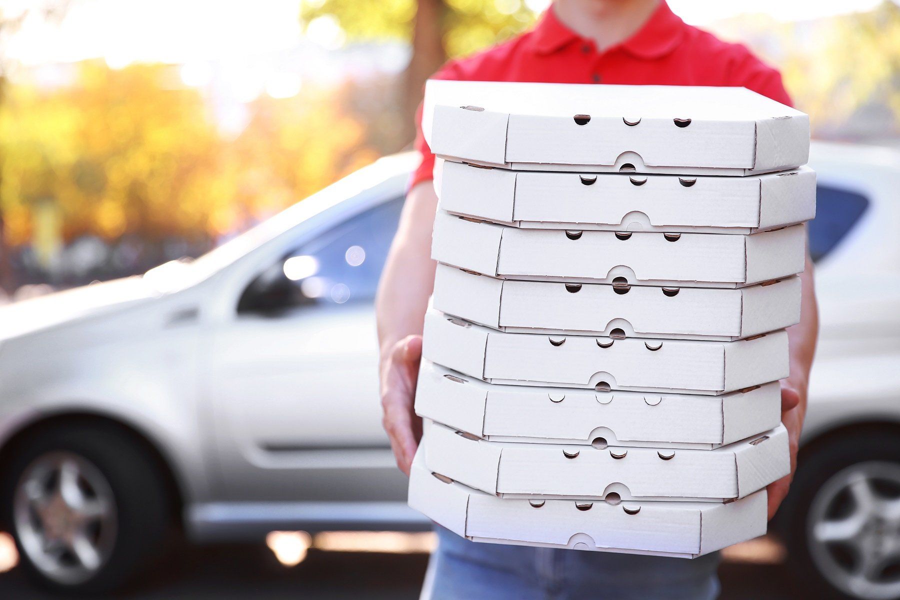 Pizza Delivery ragazzo in possesso di scatole di pizza vicino auto