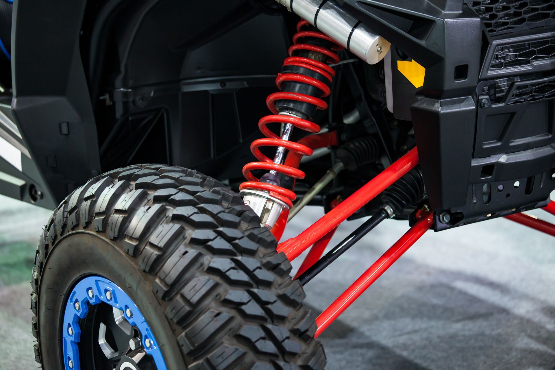 Close-up of an off-road vehicle’s rear suspension with red coil springs and a large rugged tire