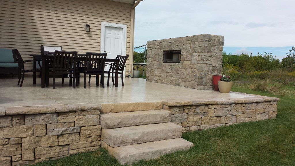 Fancy stone patio with dark seats and tables — Cedar Rapids, IA — Earthworks Concrete