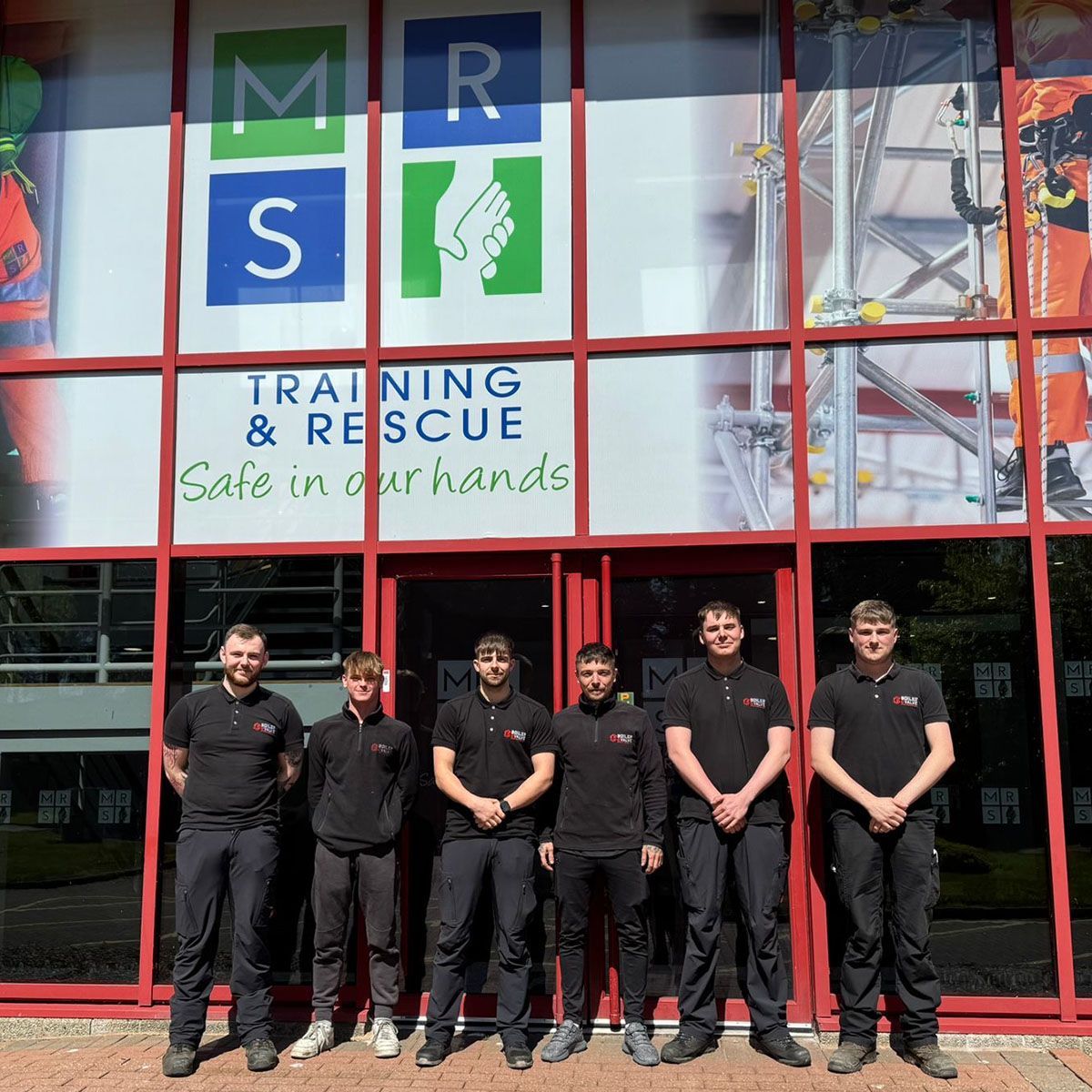 A group of men standing in front of a building that says training & rescue
