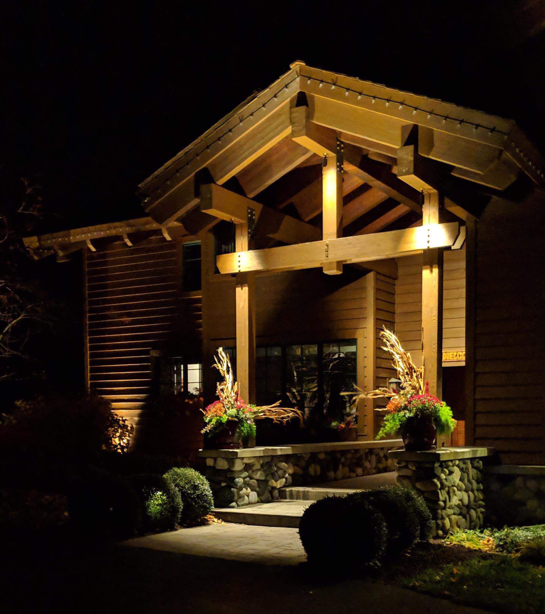 A house is lit up at night with flowers on the porch