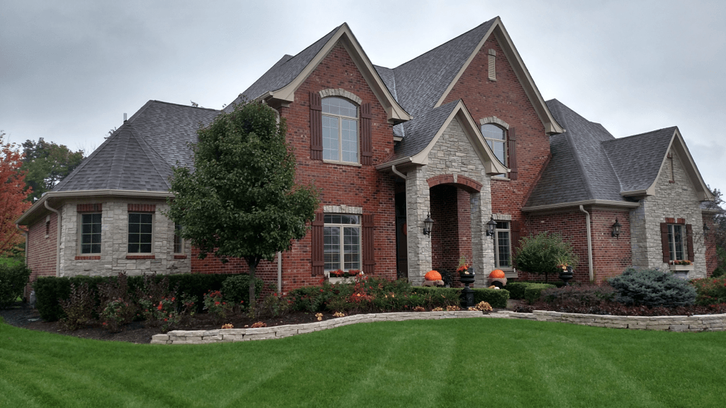 A large brick house with a lush green lawn in front of it.