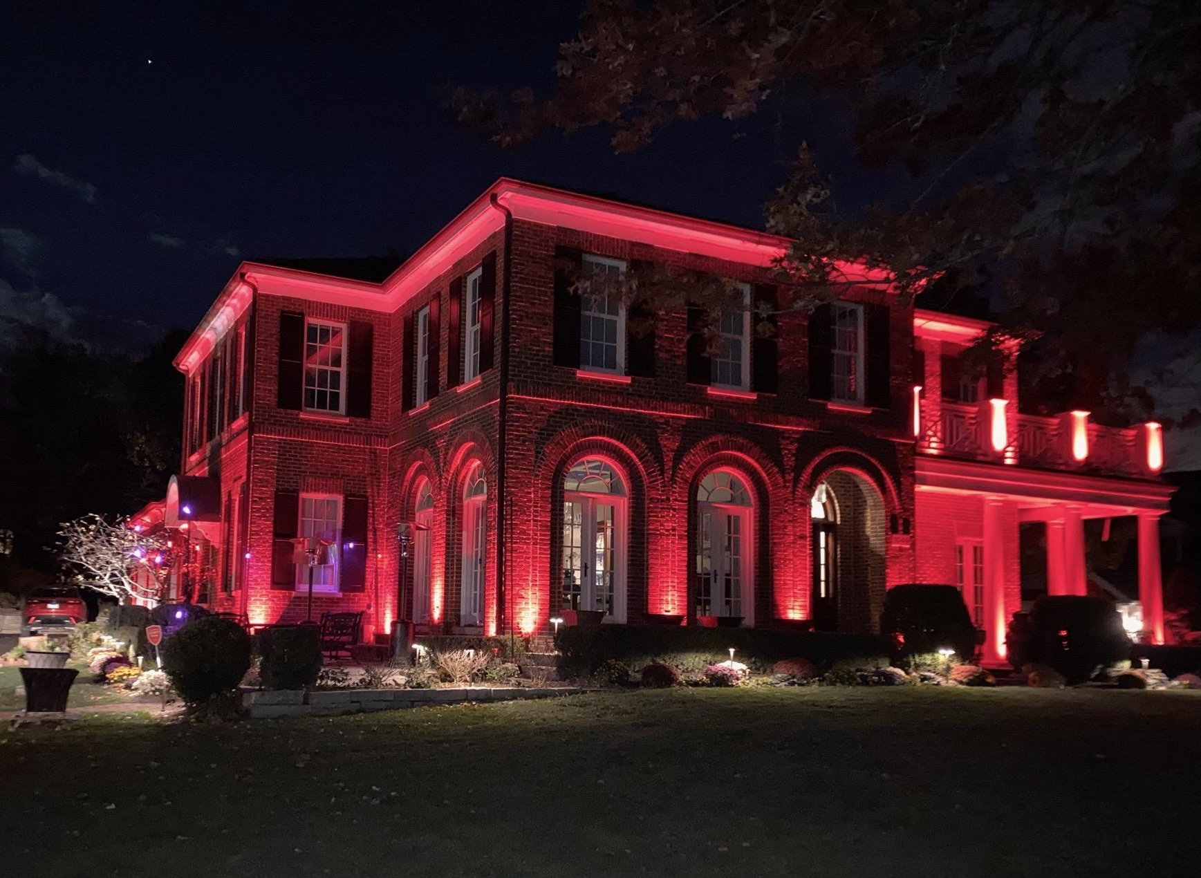 A large brick house is lit up with red lights at night