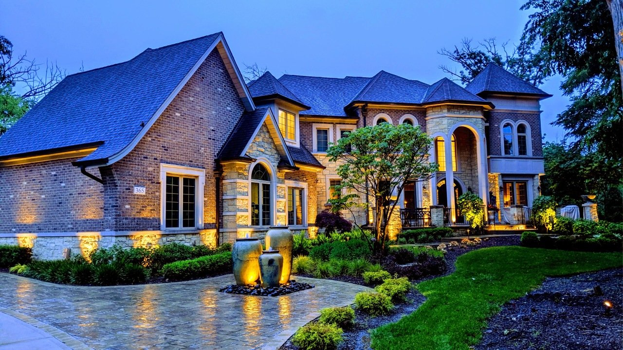 A large brick house with a blue roof is lit up at night.
