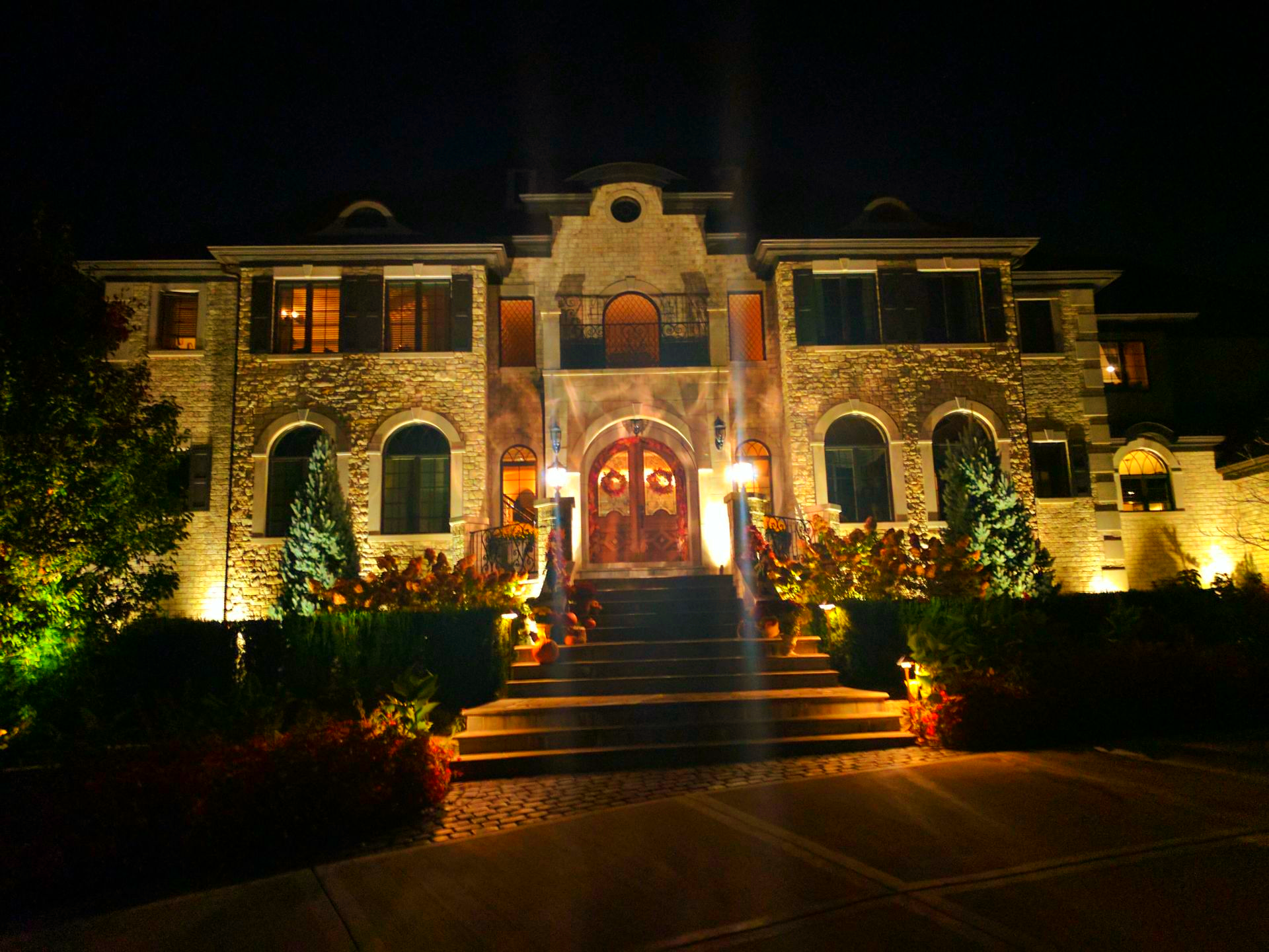 The front of a large house is lit up at night
