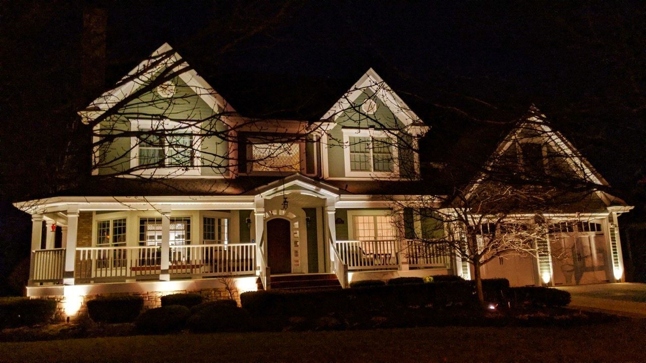 A large house with a porch is lit up at night.