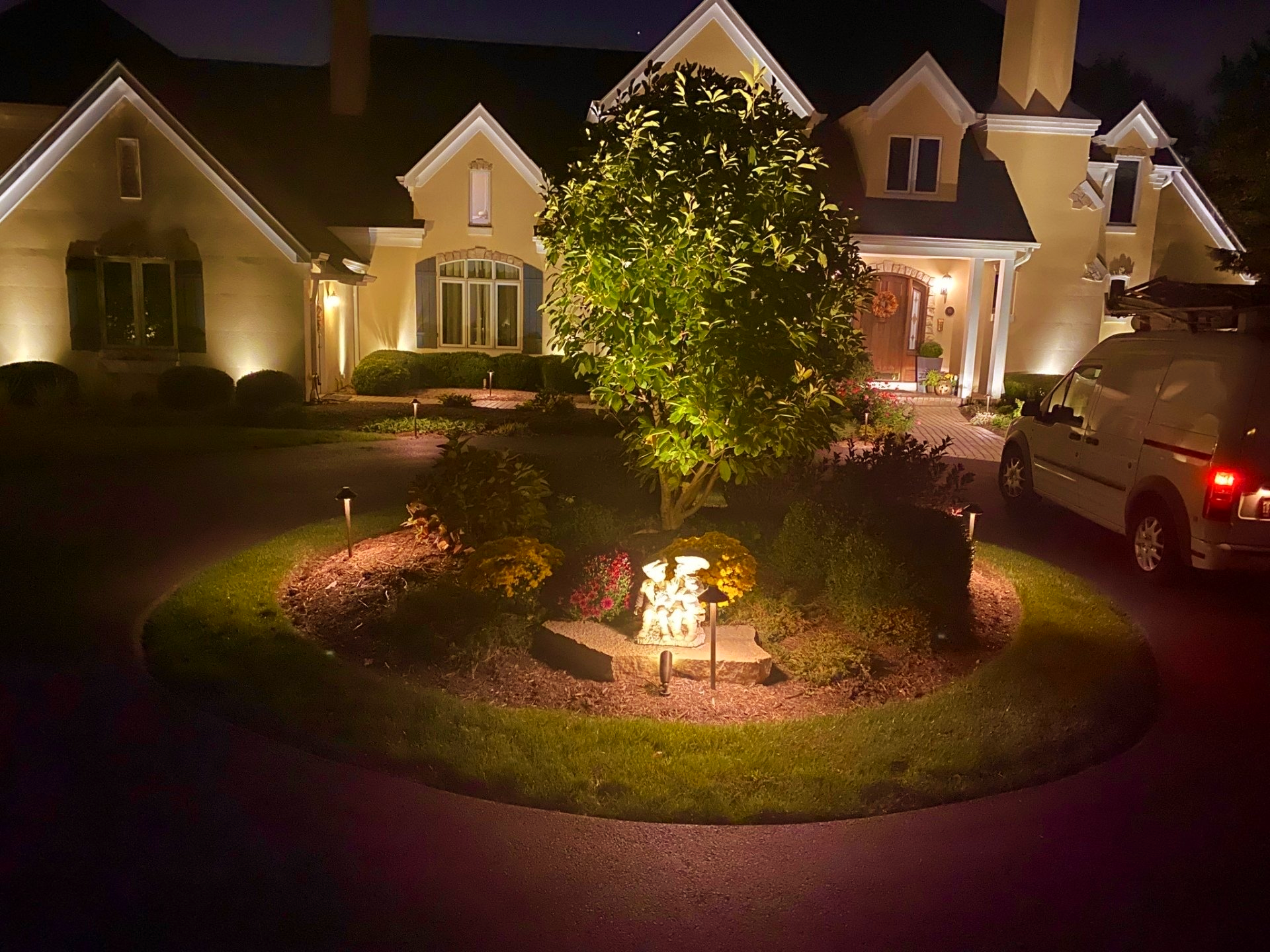 A car is parked in front of a house that is lit up at night