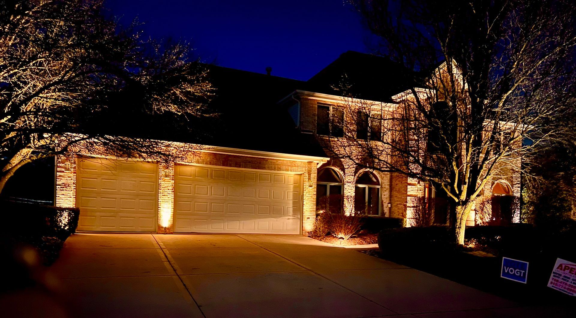 A large house is lit up at night with a truck parked in front of it