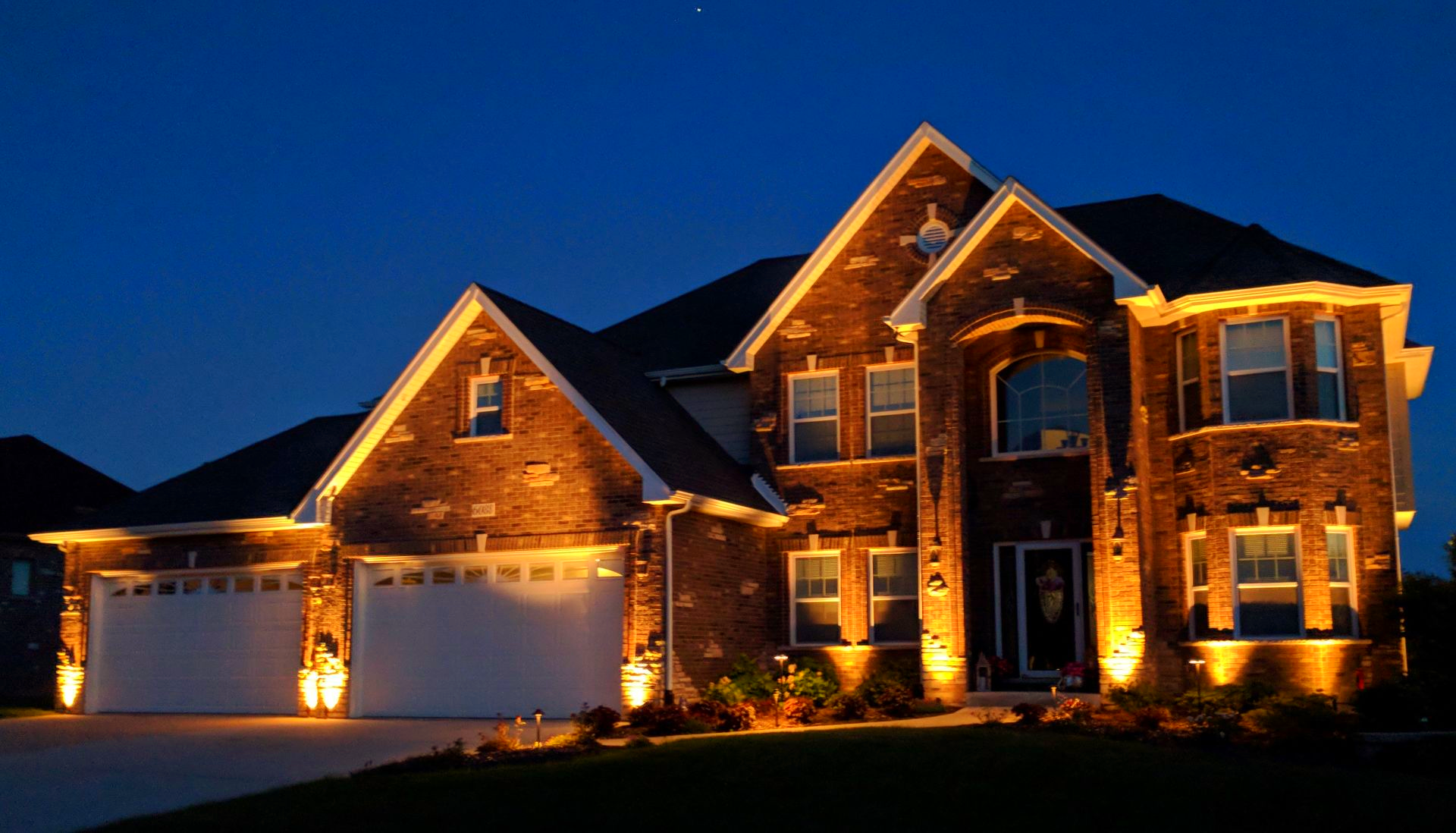 A large brick house is lit up at night