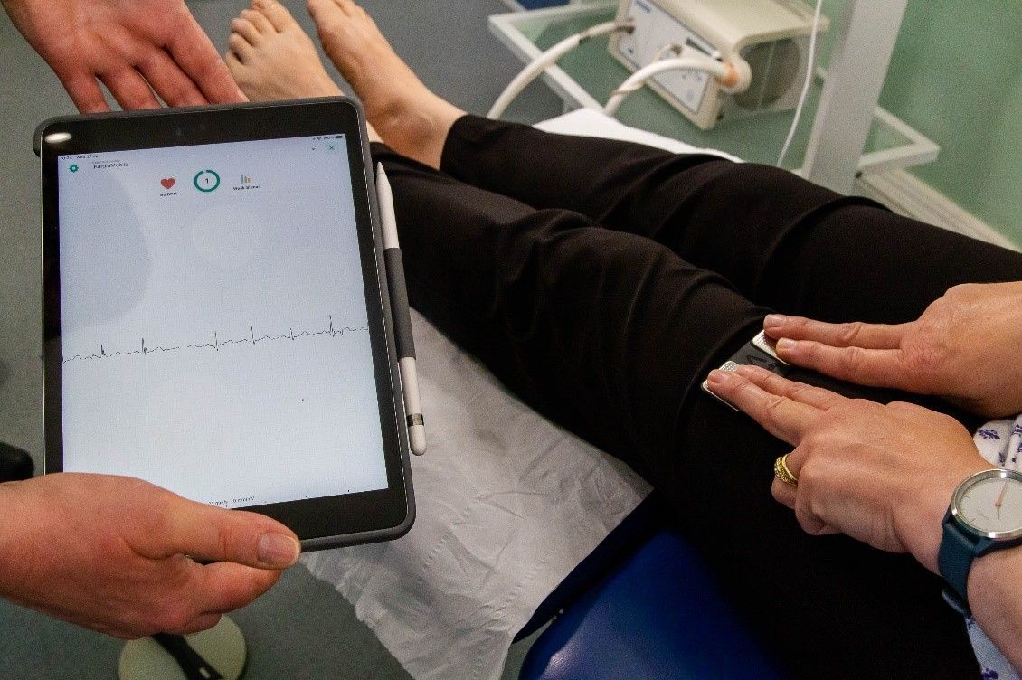 A person is holding a tablet in front of a patient 's foot.