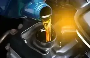 A blue jug pours amber-colored motor oil into the black oil filler cap opening of a car engine.