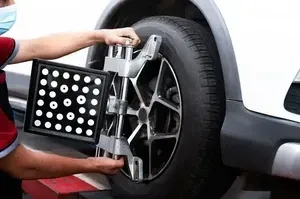 A mechanic attaches a wheel alignment sensor to the tire of a vehicle in a service shop.