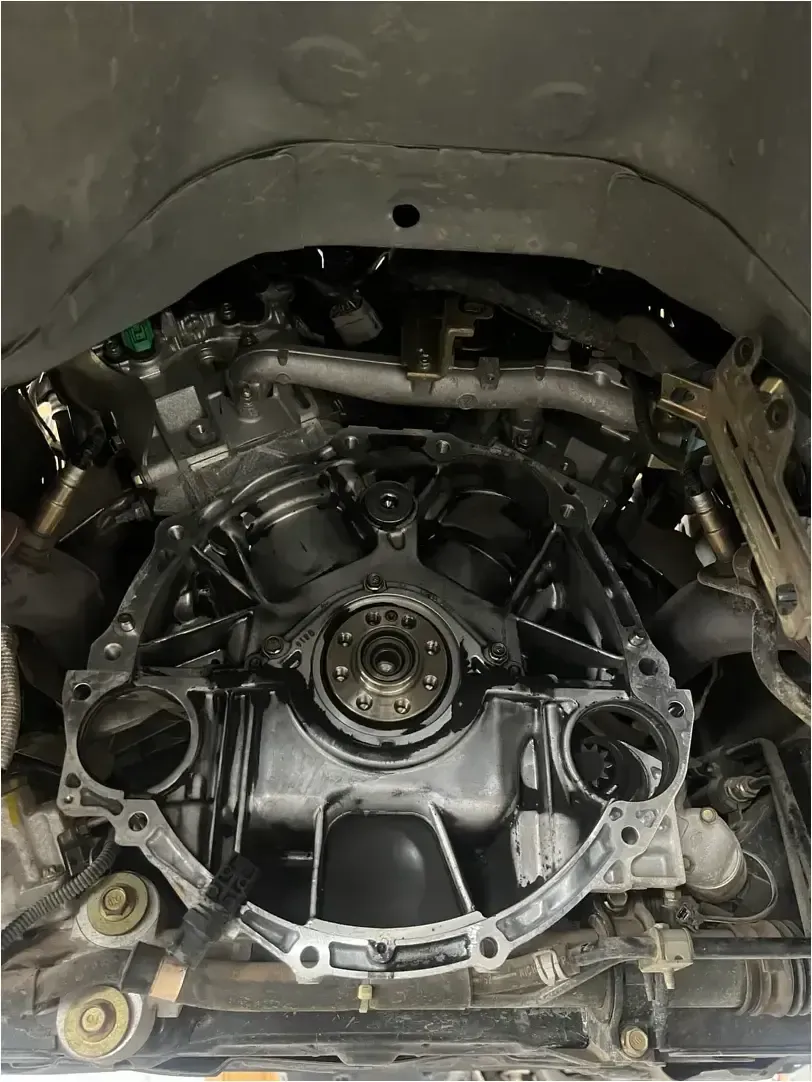 Hands in white gloves holding a metal automotive clutch release bearing against a vehicle clutch pressure plate.