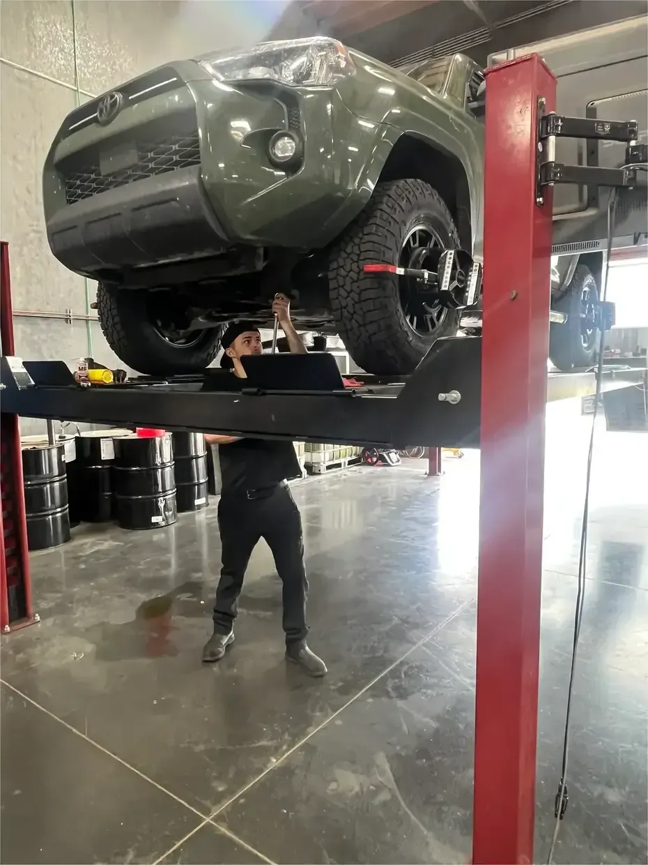 A sensor from an alignment machine attached to the tire of a bright red vehicle in a repair shop.