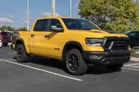 Yellow RAM pickup truck parked in a lot, shown from the front-left side.