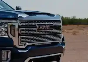 Close-up, front-facing view of a dark blue GMC truck, highlighting its large chrome grille and headlights.