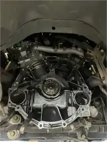 Hands in white gloves holding a metal automotive clutch release bearing against a vehicle clutch pressure plate.