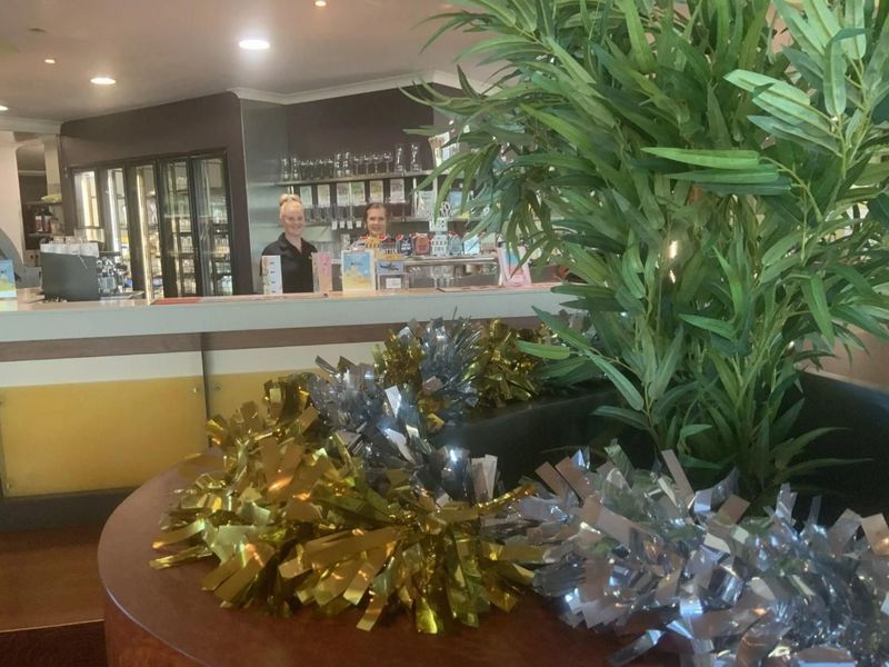 Bar With Two Employees Behind It, Decorated With Gold and Silver Tinsel — Capricorn Tavern in Taranganba, QLD