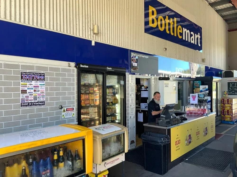A Man Stands Behind the Counter, Fridge With Beverages — Capricorn Tavern in Taranganba, QLD